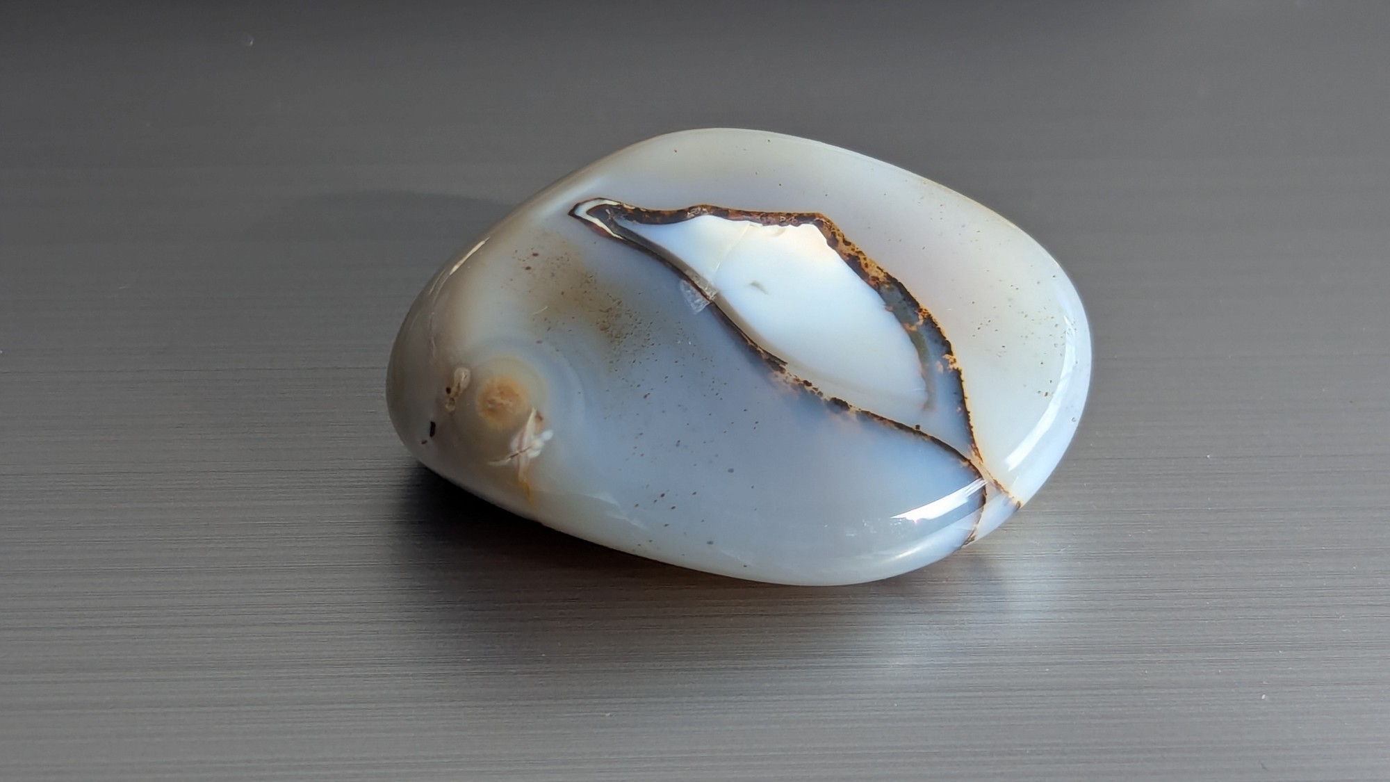 Blue-gray tumbled stone with a single black vein running straight through it