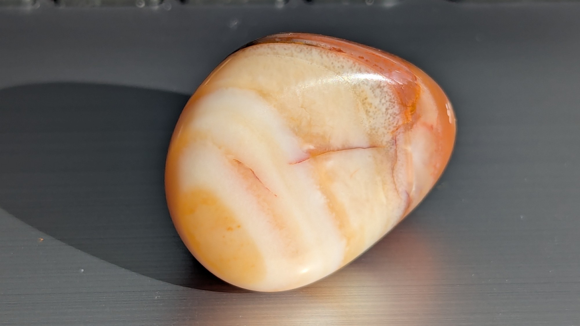 Tumbled stone with orange and cream swirled together and a few fine red lines