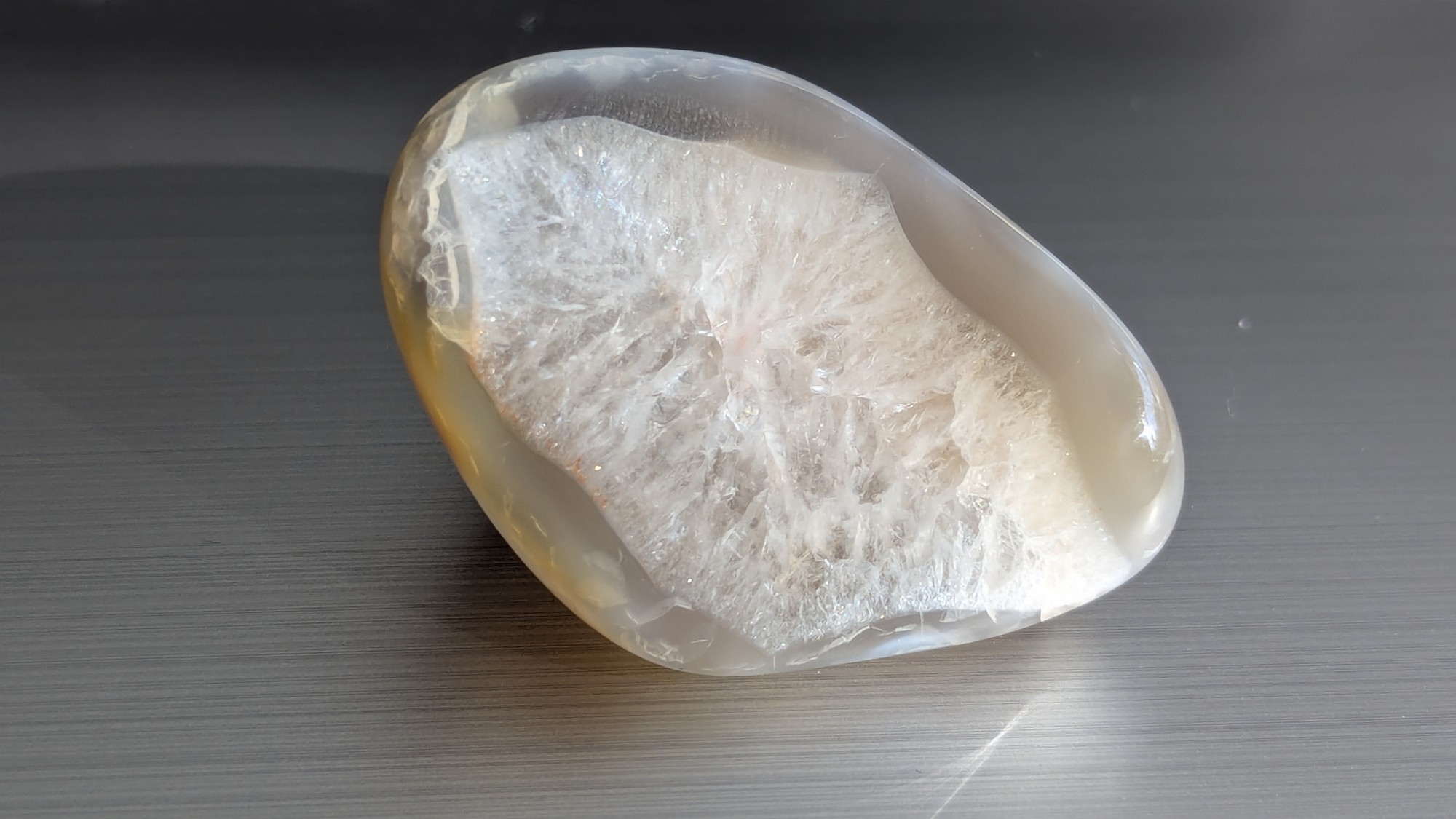 Tumbled stone with frosty crystals on one face and a smooth, clear surface on the other