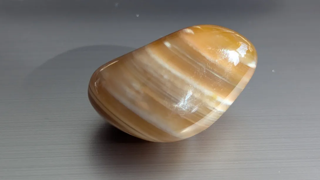 Tumbled stone with honey-colored bands lit by direct sun