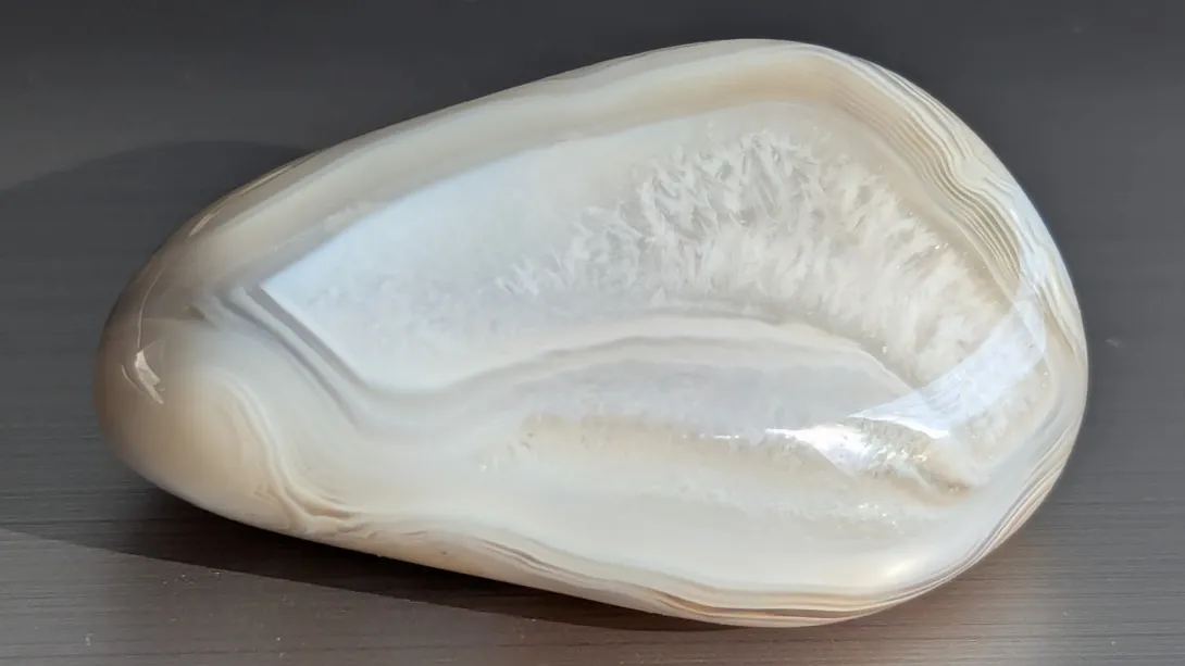 Large white tumbled stone with a window of tiny crystals along the top and fine banding around the edge
