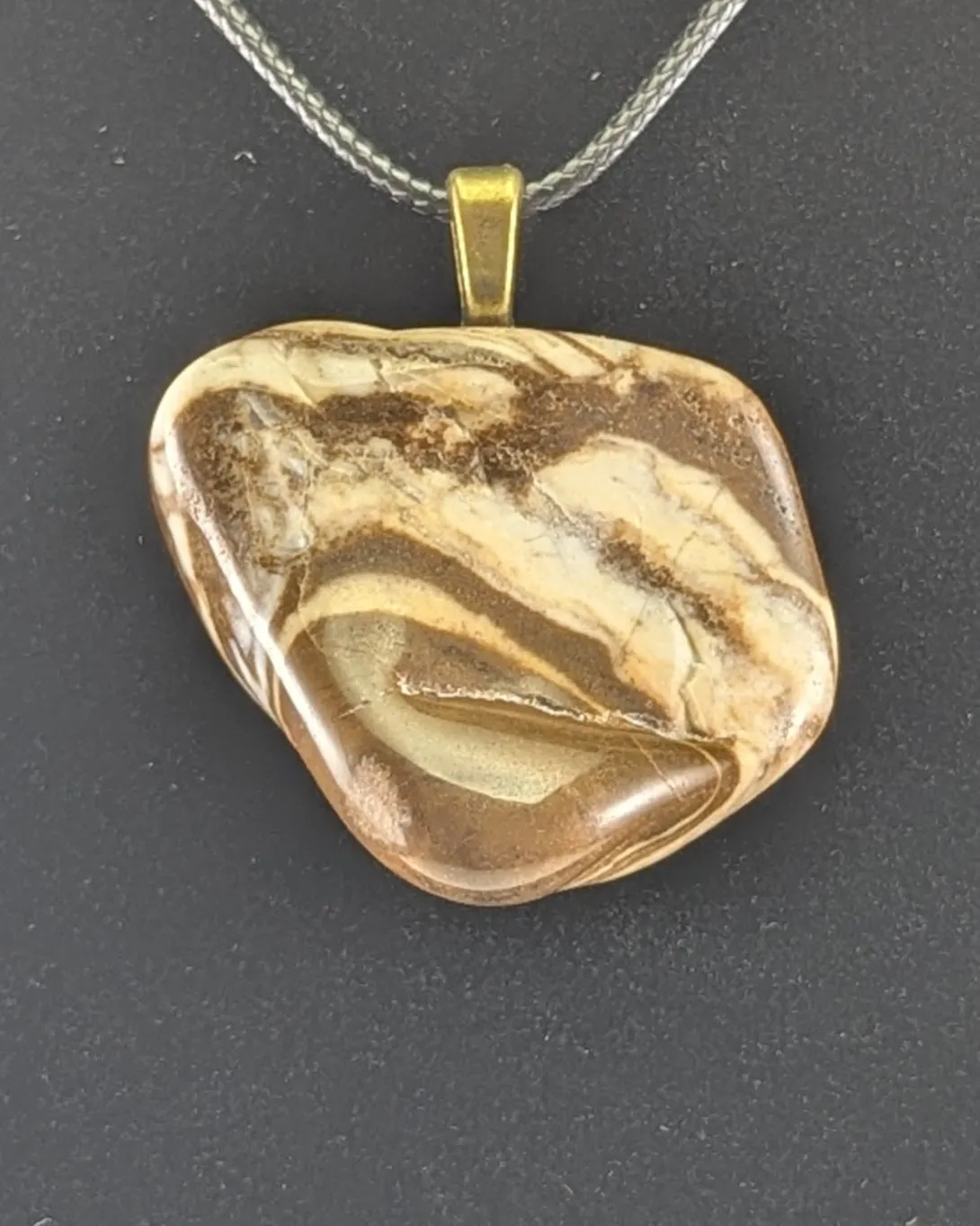 Zebra jasper pendant with swirling brown and cream stripes on a brass-tone bail